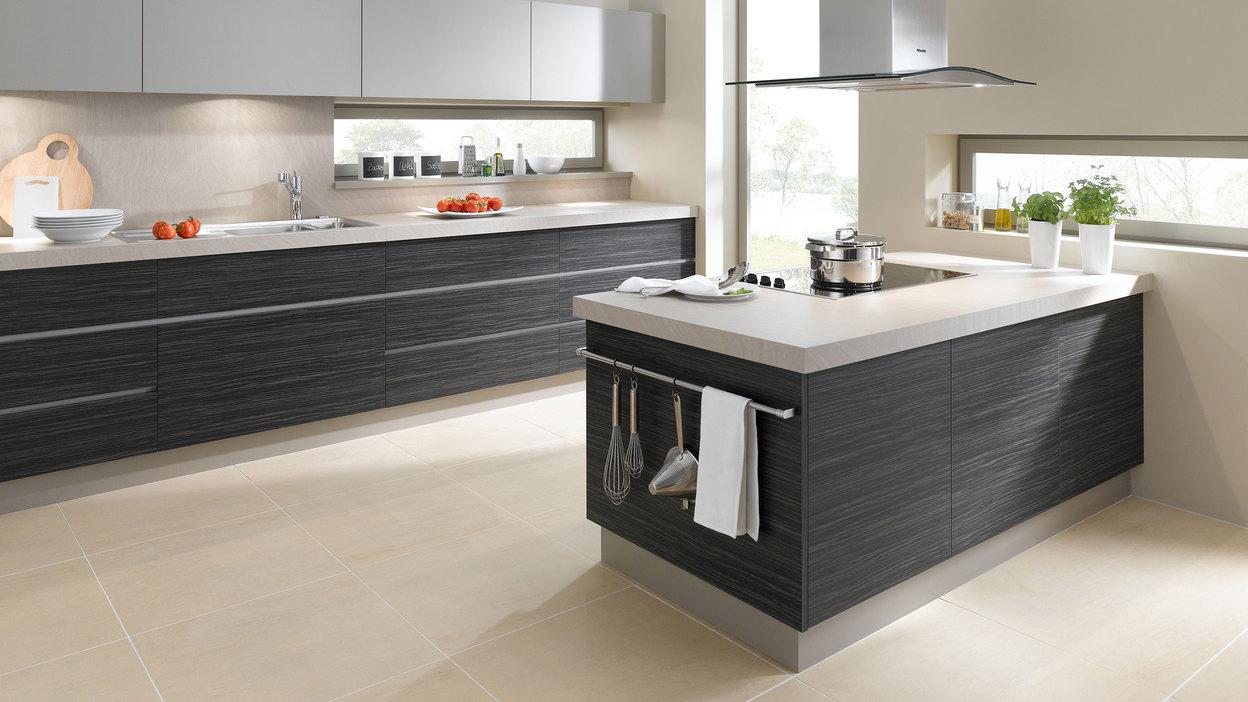Impression einer Küchengestaltung mit Kochinsel mit Edelstahlabzug und dunklen Fronten